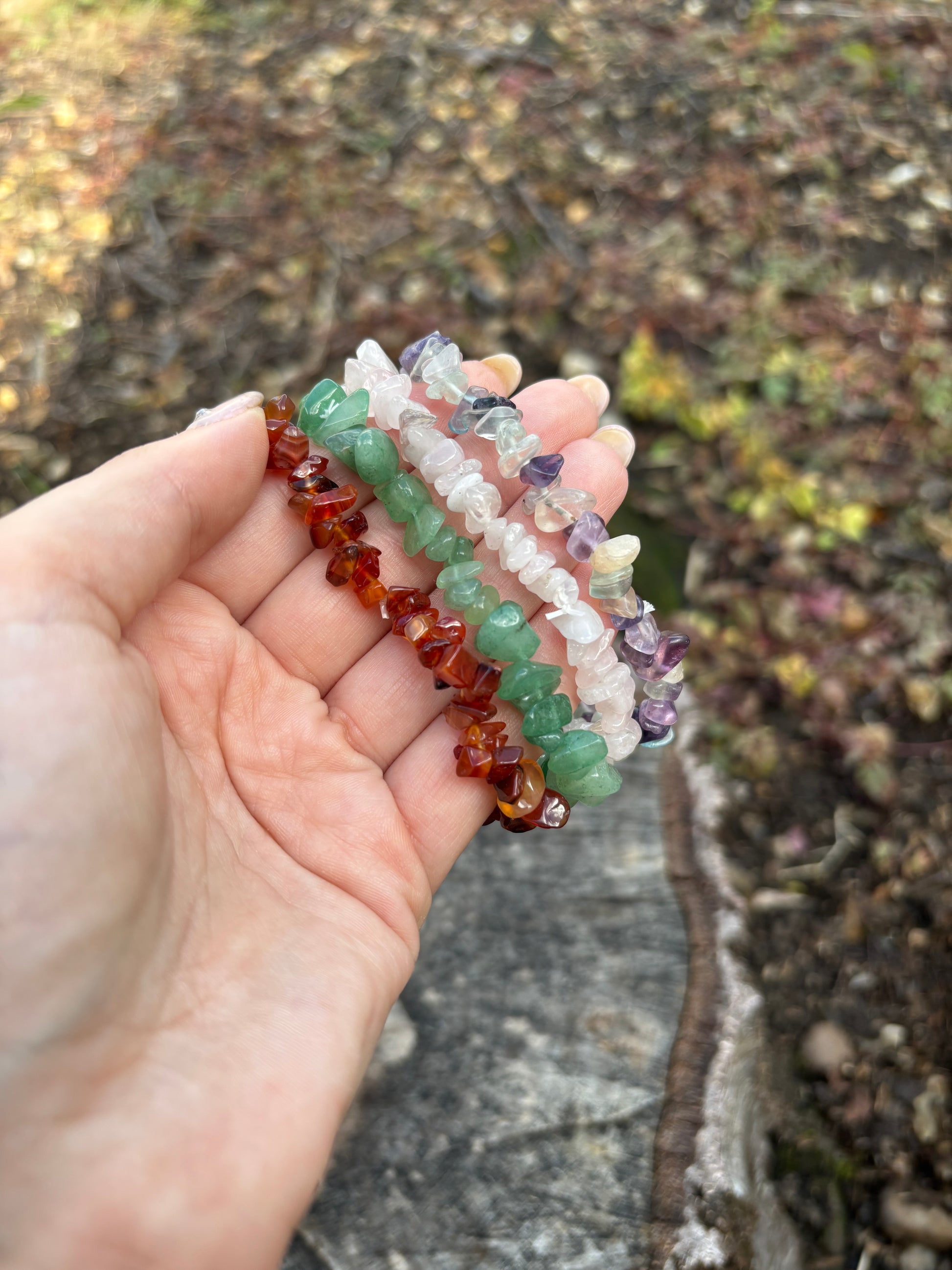 Hand holding a stack of colorful beaded bracelets against a natural background