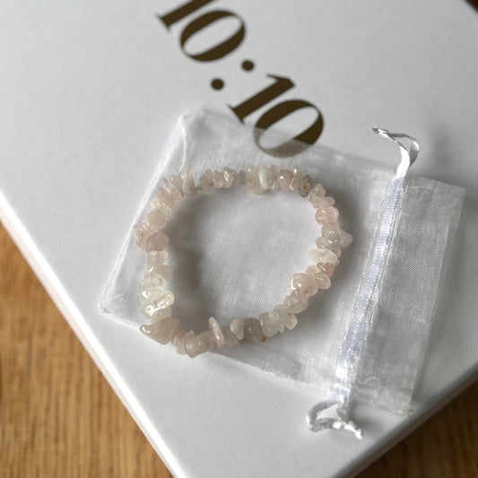 Crystal bracelet in clear packaging on a white surface with '10:10' branding.  Rose Quartz crystal bracelet for self-love, emotional healing, and heart chakra balance. A wearable ritual for compassion, confidence, and calm.